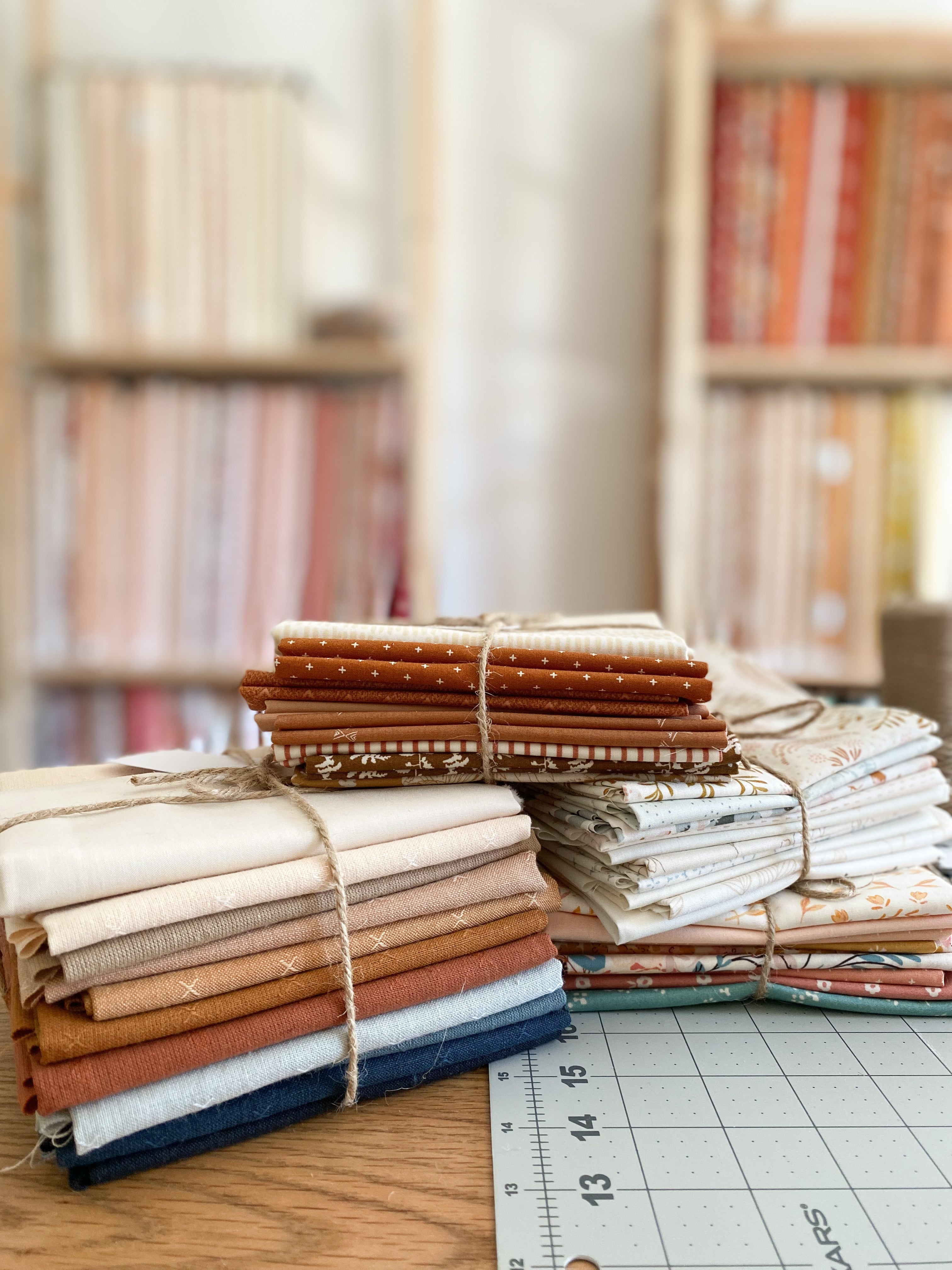 Bundles of fabric fat quarters tied with twine on cutting mat in charming fabric shop